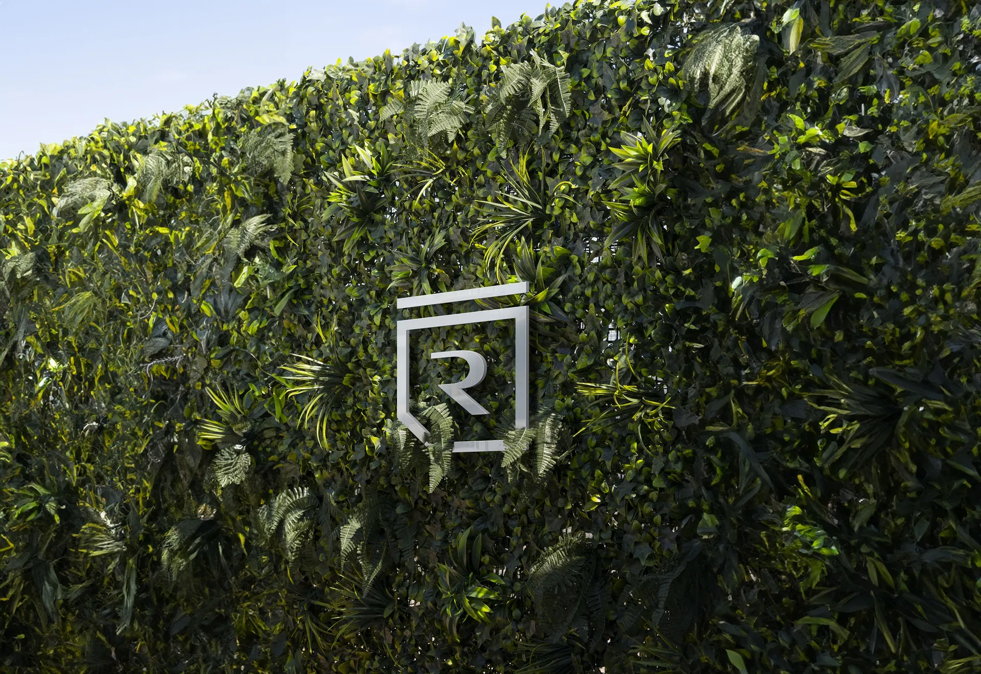 Identidade Rigma — logo metálico sobre jardim vertical